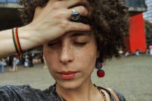 close up photo of woman with her eyes closed holding her forehead
