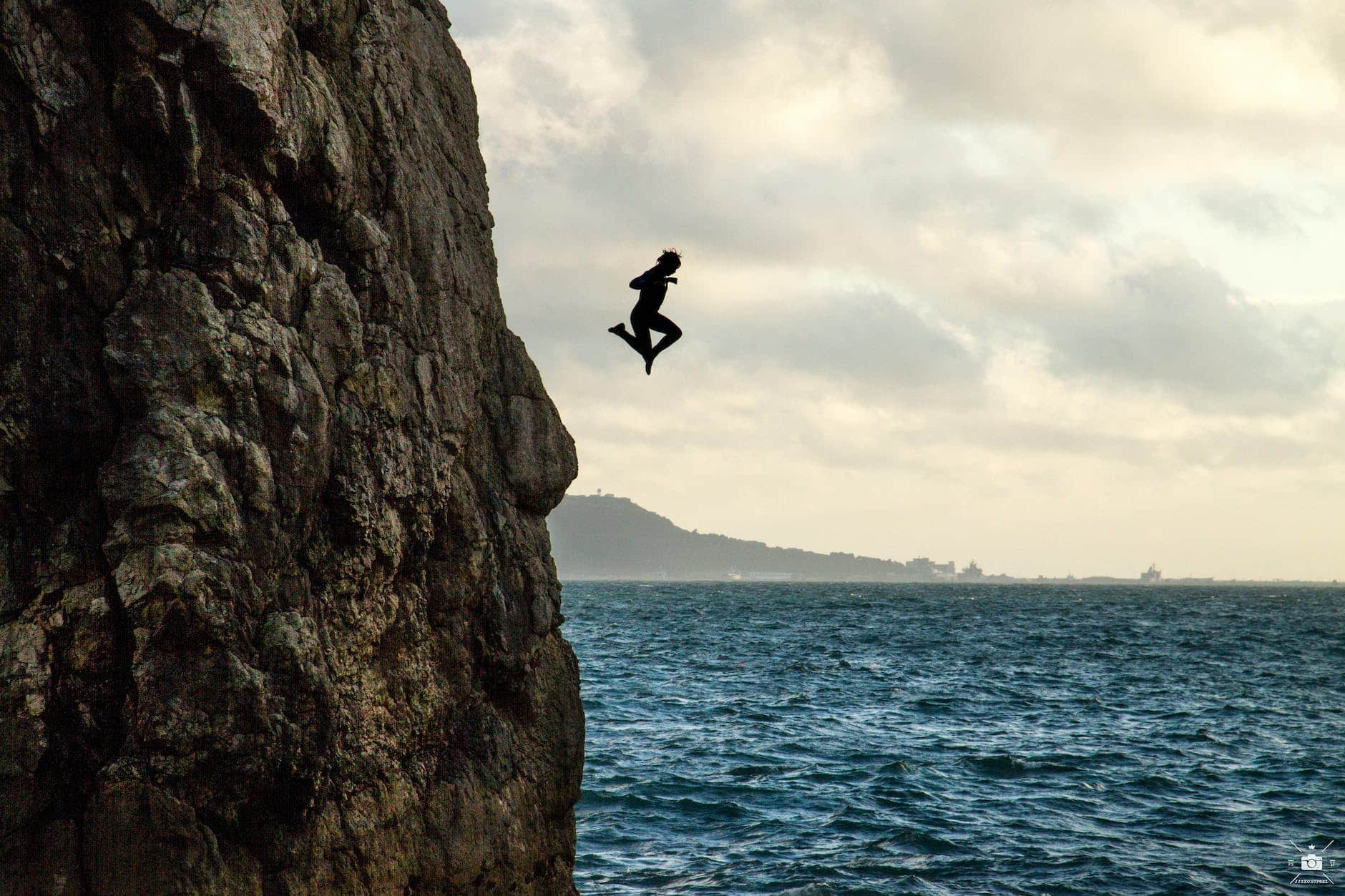 anonymous brave person jumping into sea water form cliff