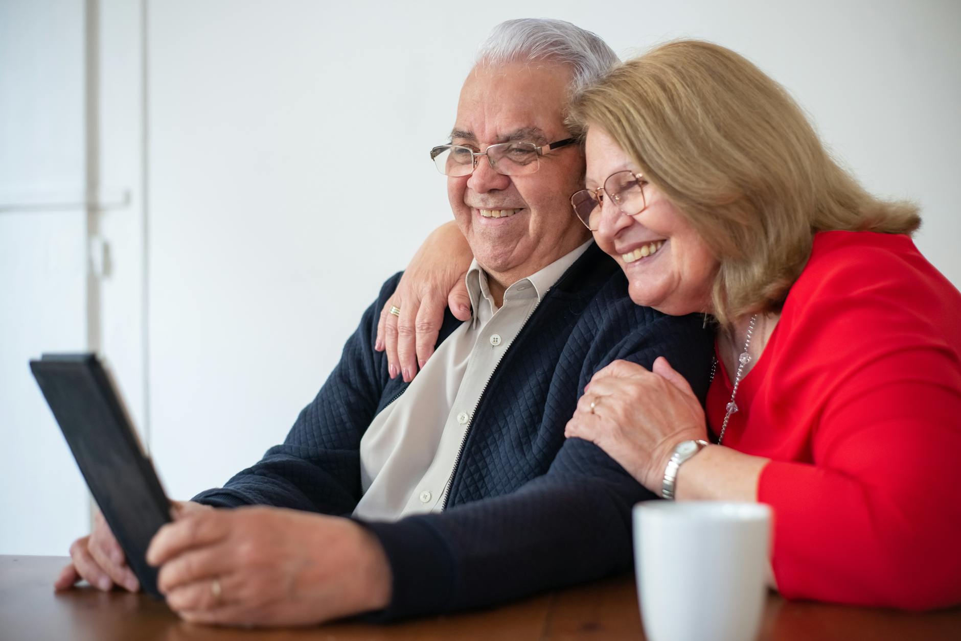 man in black jacket sitting beside woman in red long sleeve shirt smiling