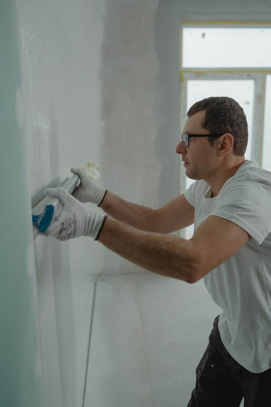 a man in white shirt painting a house