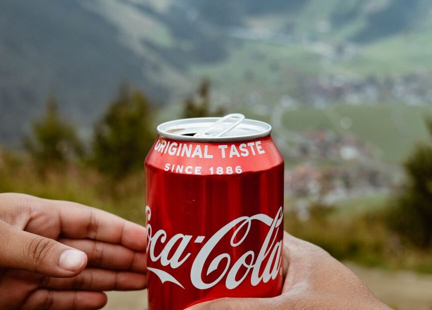 a person passing a can of soda