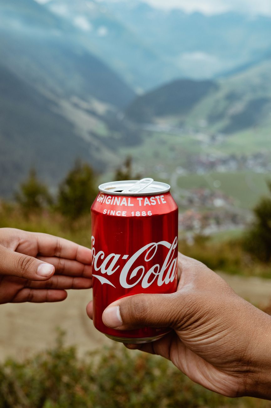 a person passing a can of soda